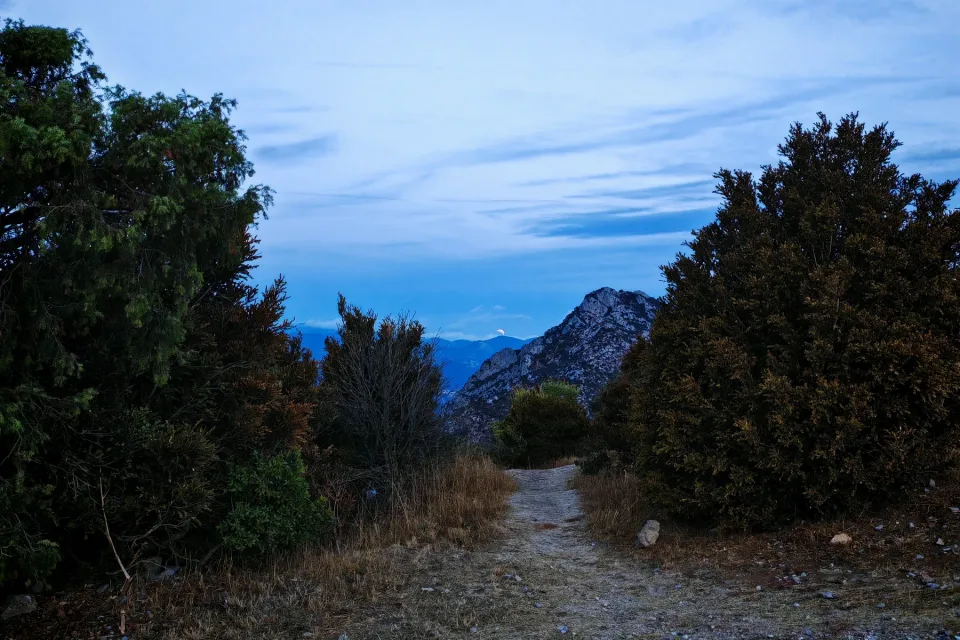 Low Moon above distant mountains beyond a path near the Quéribus parking area at dawn