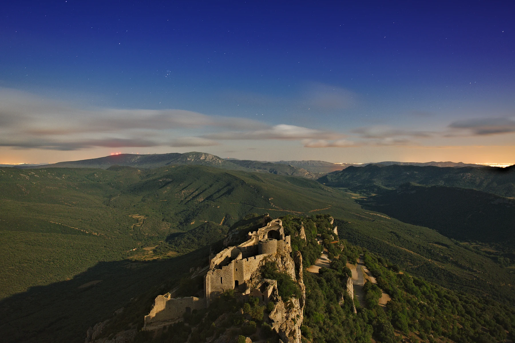 Night photograph of Peyrepertuse Castle beneath a blue star-filled sky in Aude, France