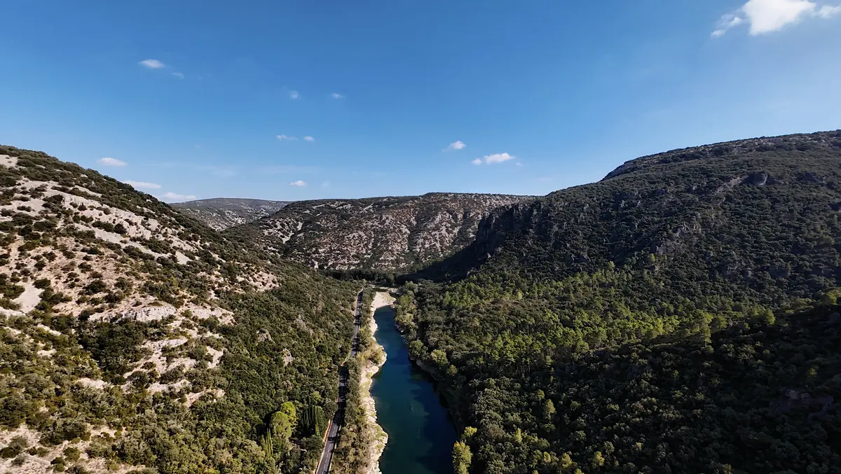 The Hérault River and a narrow road winding between rocky wooded slopes in southern France