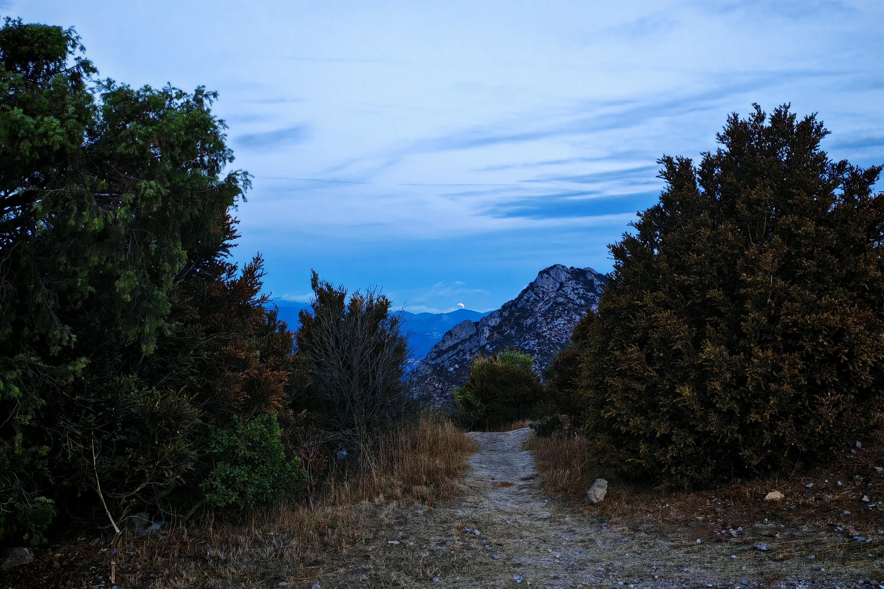 Low Moon above distant mountains beyond a path near the Quéribus parking area at dawn